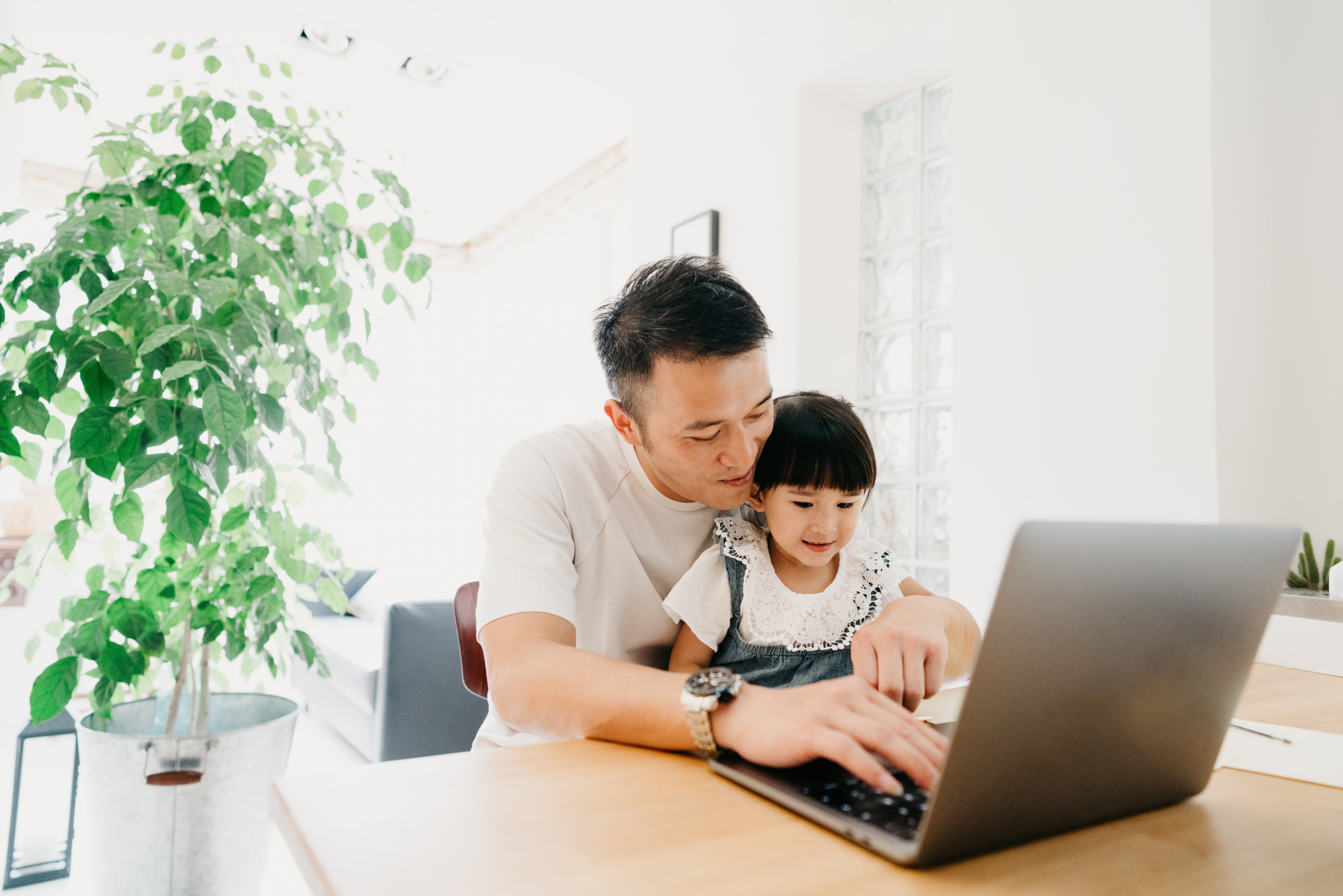 father and child sitting in front of a laptop